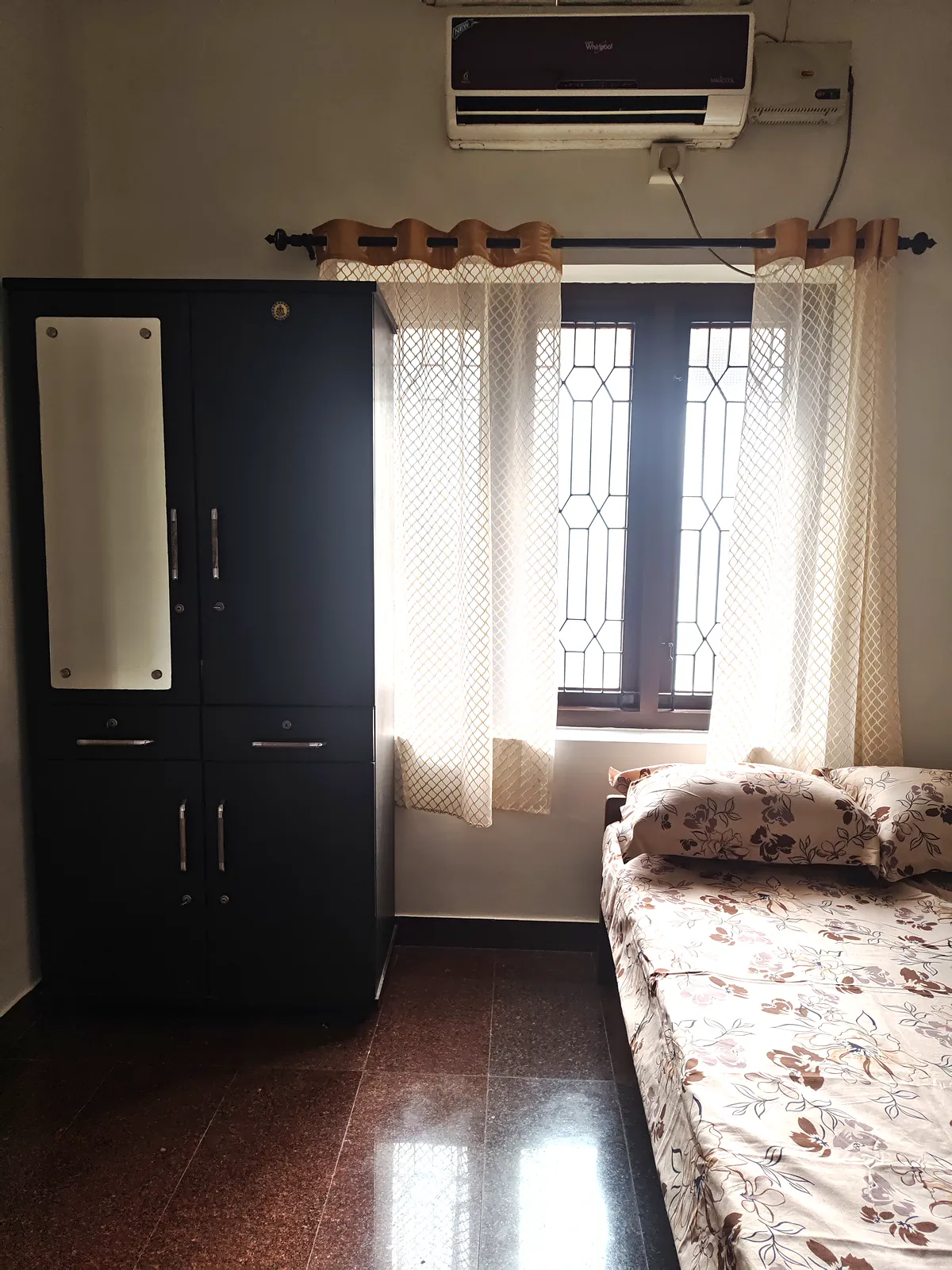 Air-conditioned ensuite bedroom on the first floor with a tall wardrobe beside a curtained window